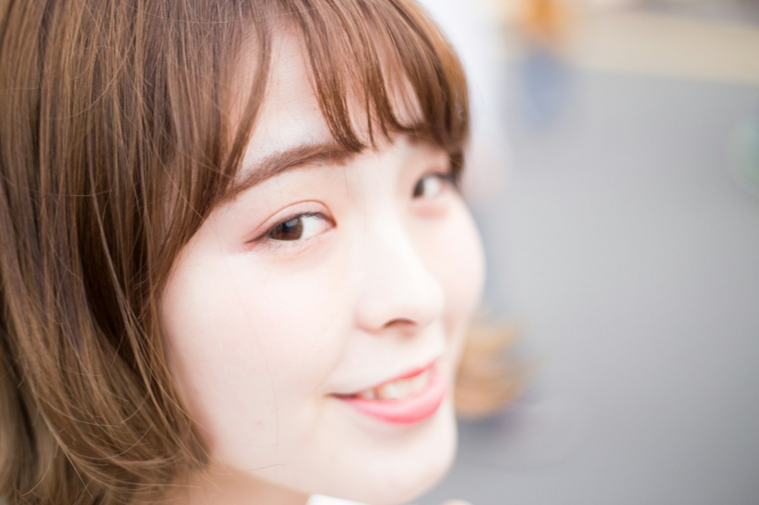 Foto en primer plano de una mujer sonriendo con una expresión brillante y un color de cabello suave