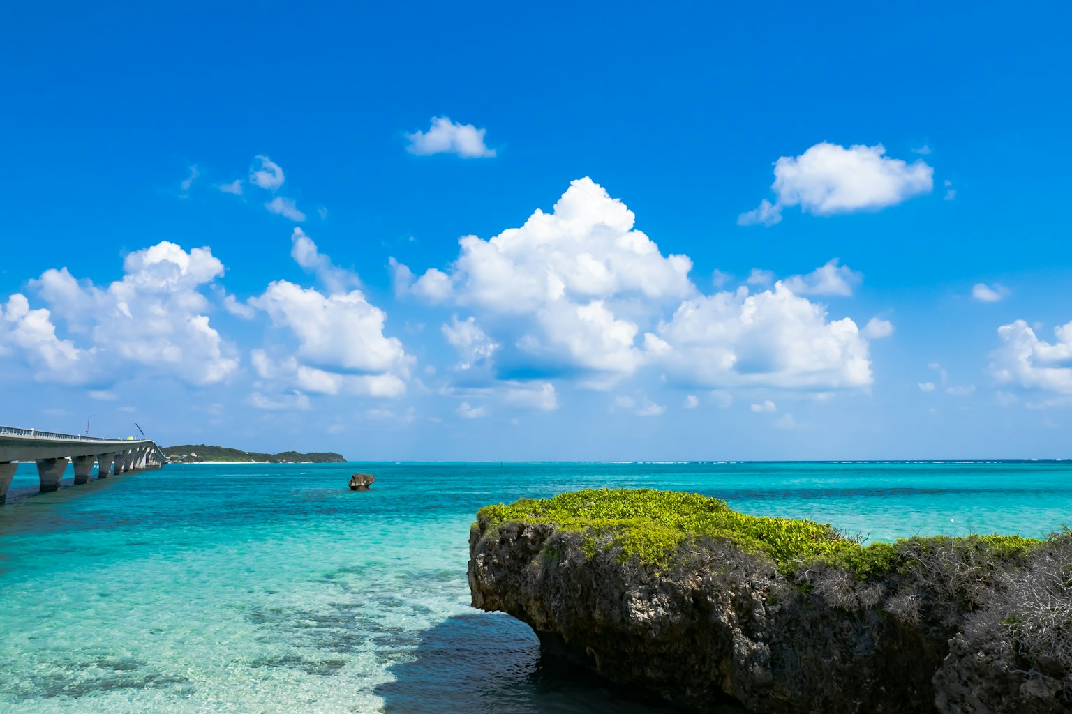 ทิวทัศน์ที่สวยงามของทะเลสีน้ำเงินและเมฆสีขาว พร้อมน้ำใสและหินสีเขียว