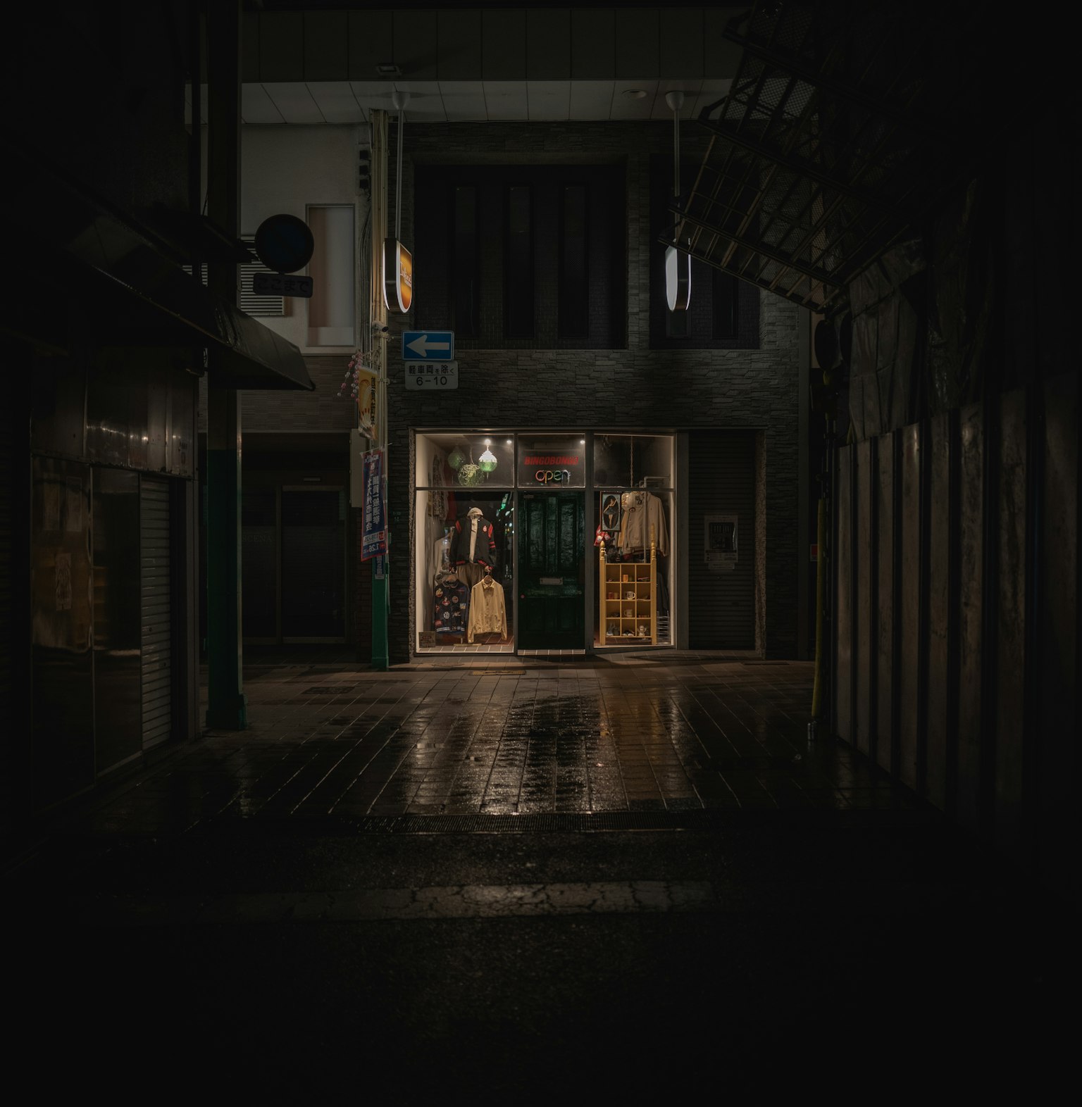 어두운 거리의 상점 입구가 보이는 비 오는 밤 장면