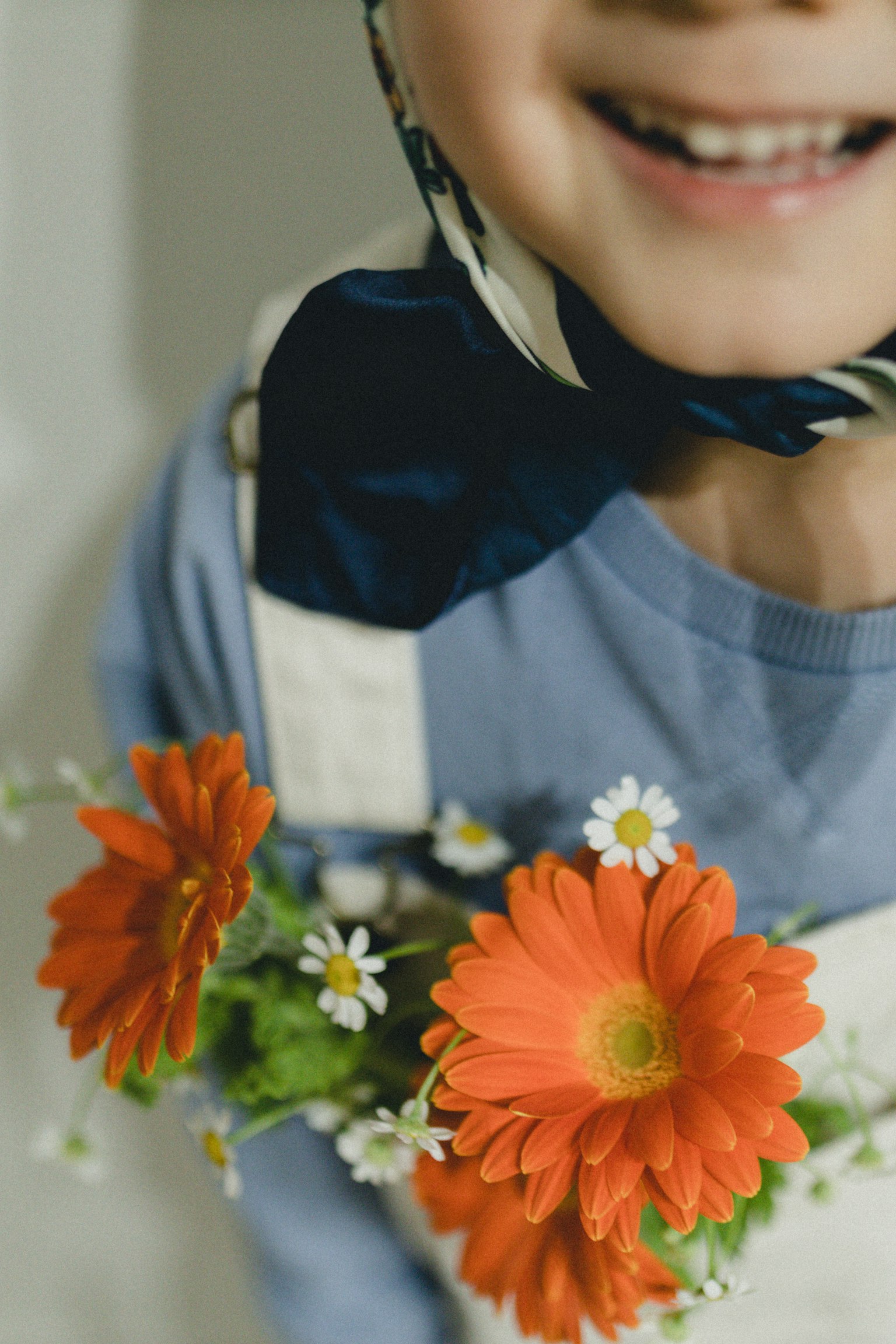 Enfant souriant tenant des fleurs orange