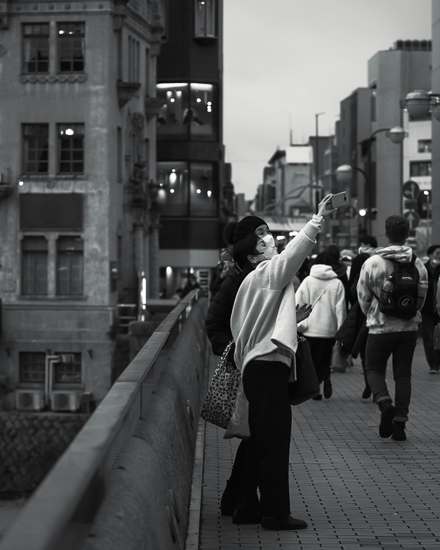 A person pointing in a black and white city scene with buildings and pedestrians