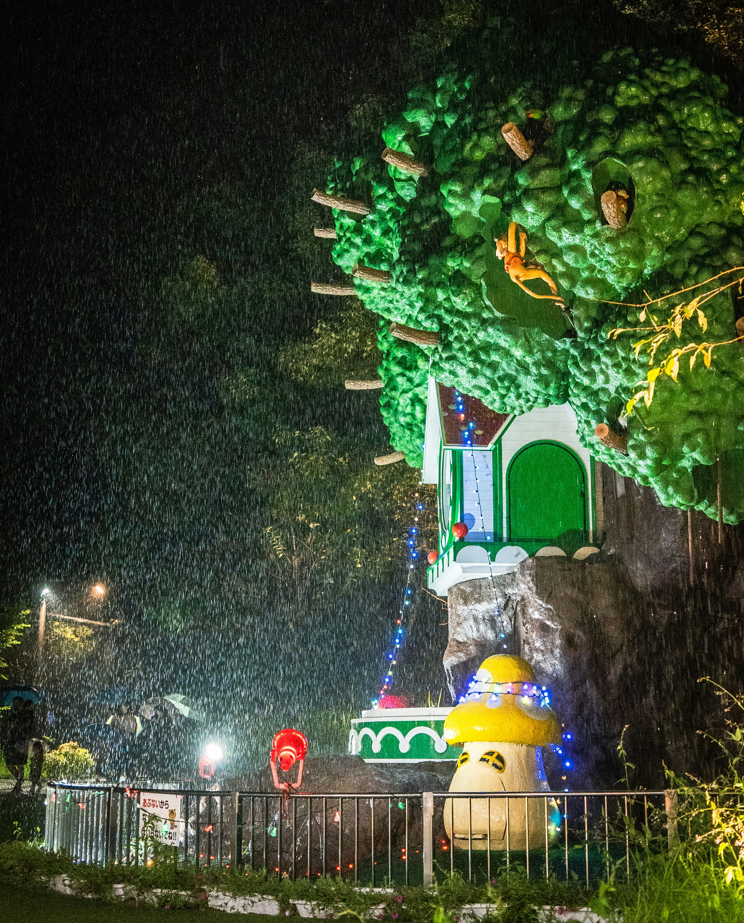 夜のイルミネーションで飾られたトンネル状の装飾と噴水風オブジェのある庭