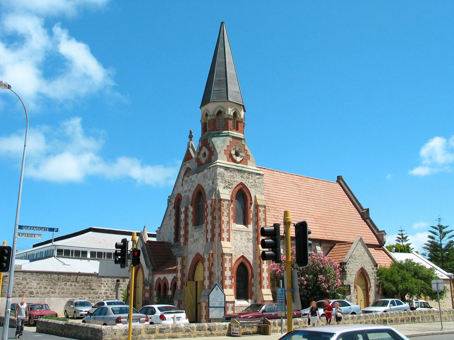 Kirchengebäude mit roter Backsteinfassade unter blauem Himmel und weißen Wolken