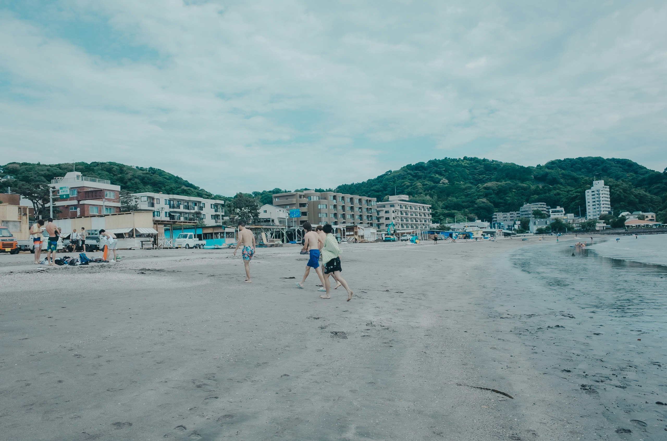 海辺の砂浜を歩く人々と海沿いの街並み
