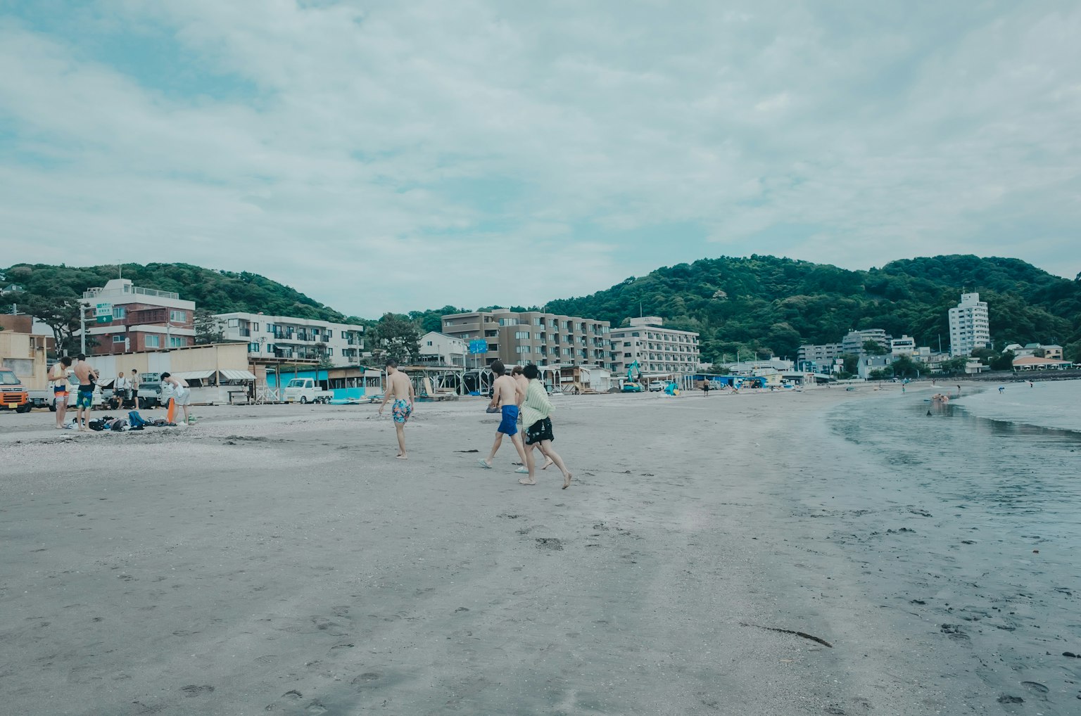 Personas jugando en la playa con montañas al fondo