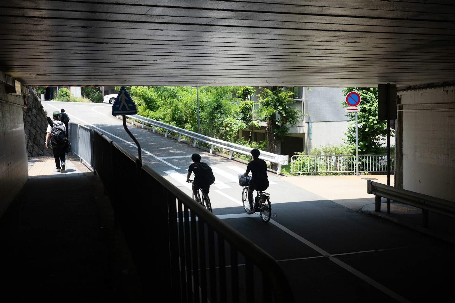 Personnes marchant et faisant du vélo sous un tunnel avec de la verdure en arrière-plan