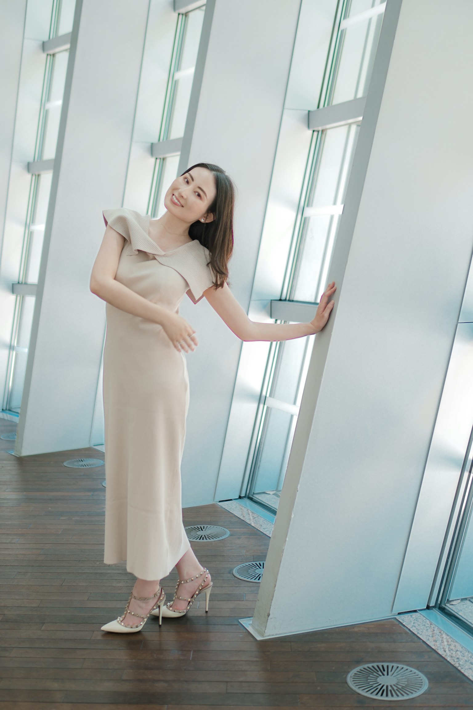 ผู้หญิงในชุดสีขาวโพสในอาคารที่มีพื้นหลังสถาปัตยกรรมสมัยใหม่