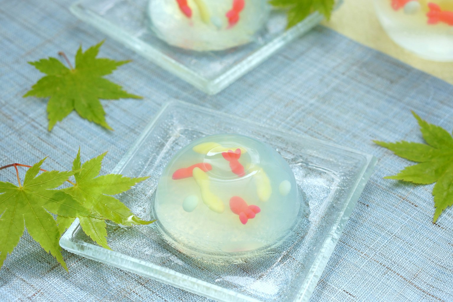 透明甜点，上面有金鱼形状的配料和绿色叶子