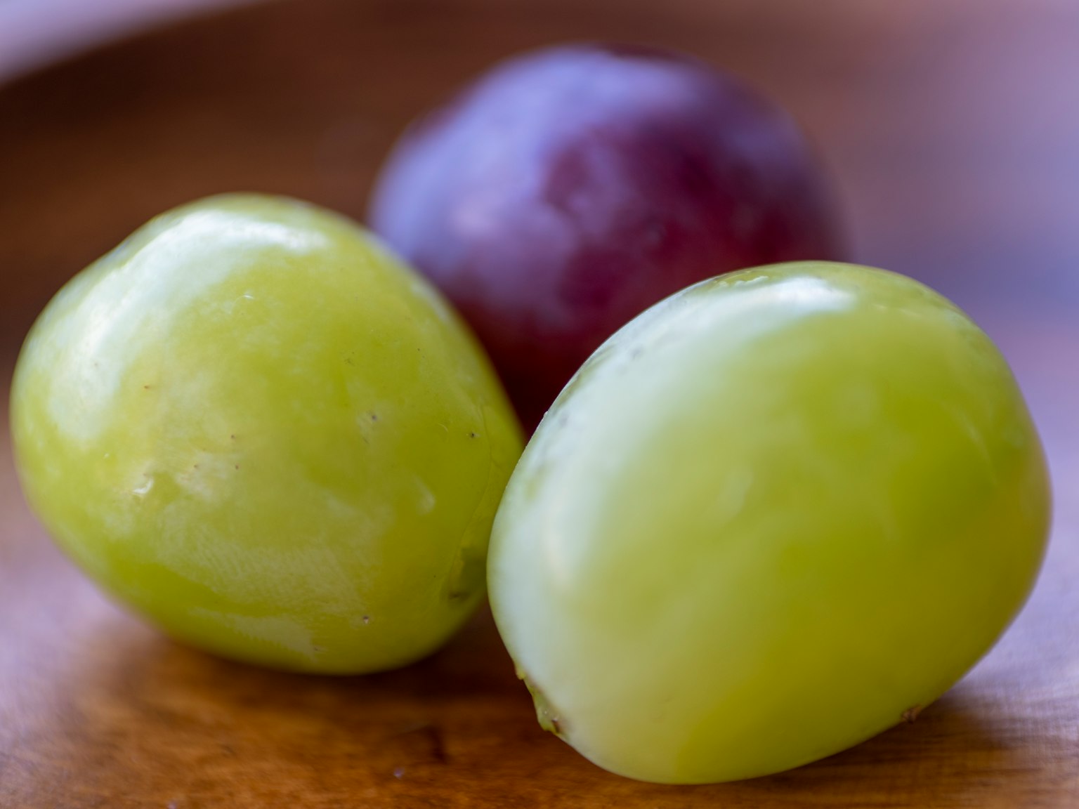 Uva verde e rosso-viola su un piatto di legno
