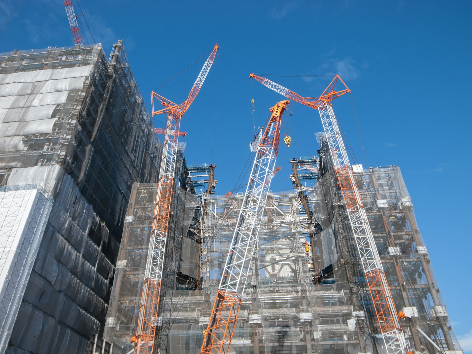 Situs konstruksi dengan crane dan perancah di bawah langit biru yang cerah