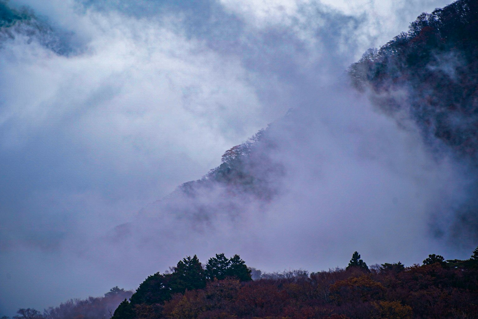 Paisaje montañoso envuelto en niebla con un hermoso contraste entre el cielo azul y las nubes