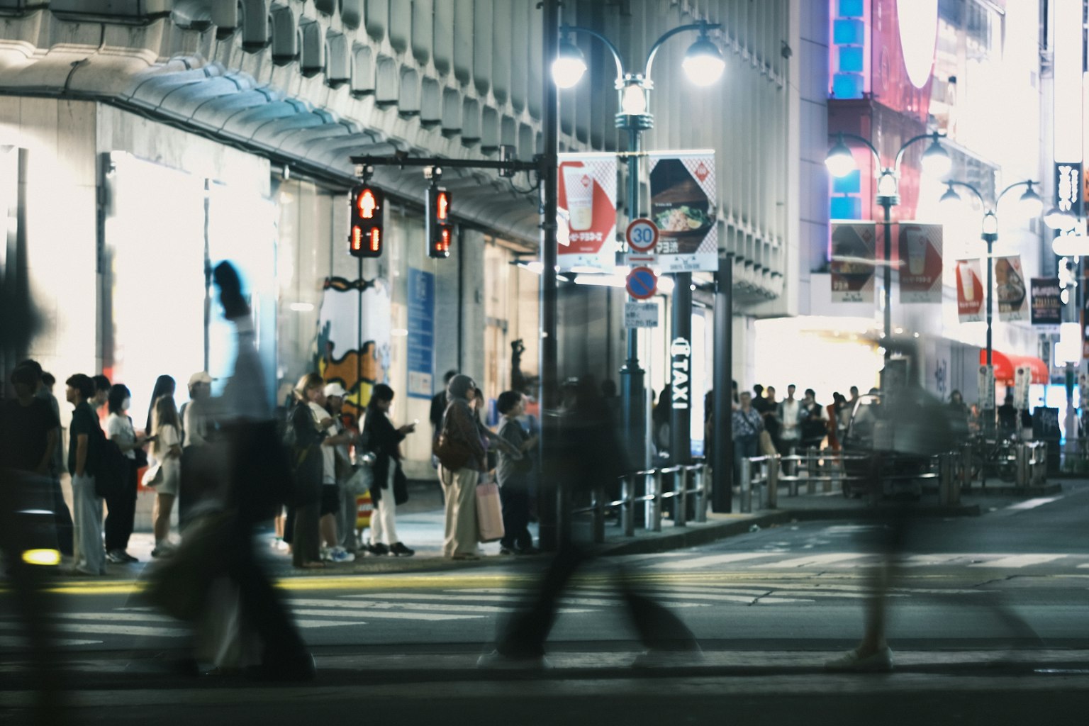 Personas cruzando la calle en el cruce de Shibuya por la noche