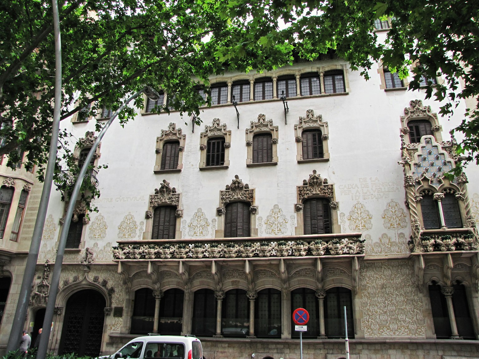 Bâtiment Art Nouveau à Barcelone façade blanche entourée d'arbres verts fenêtres décoratives