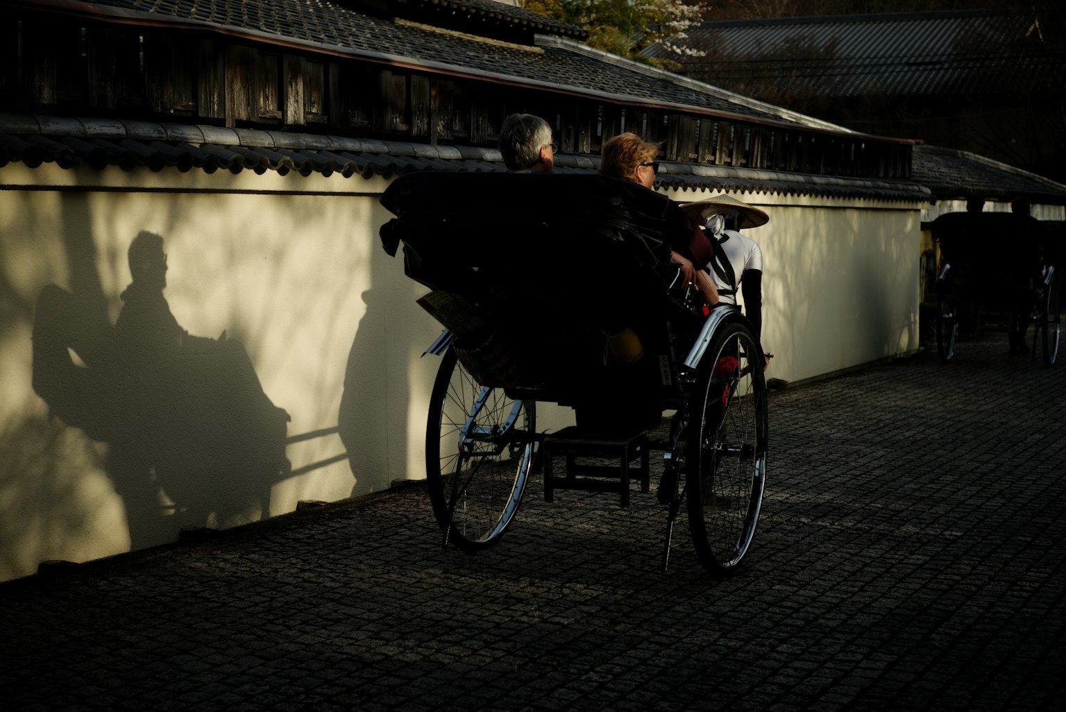 Deux personnes dans une rickshaw avec des ombres projetées sur un mur