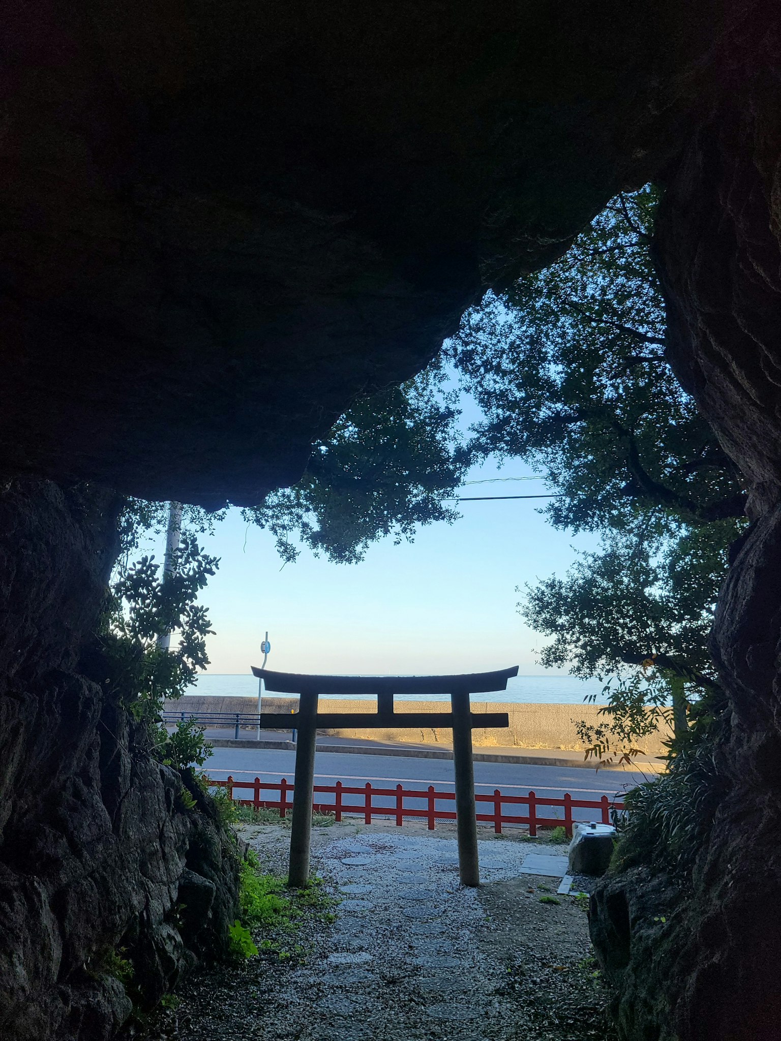Vue d'un torii à travers une grotte avec une plage en arrière-plan