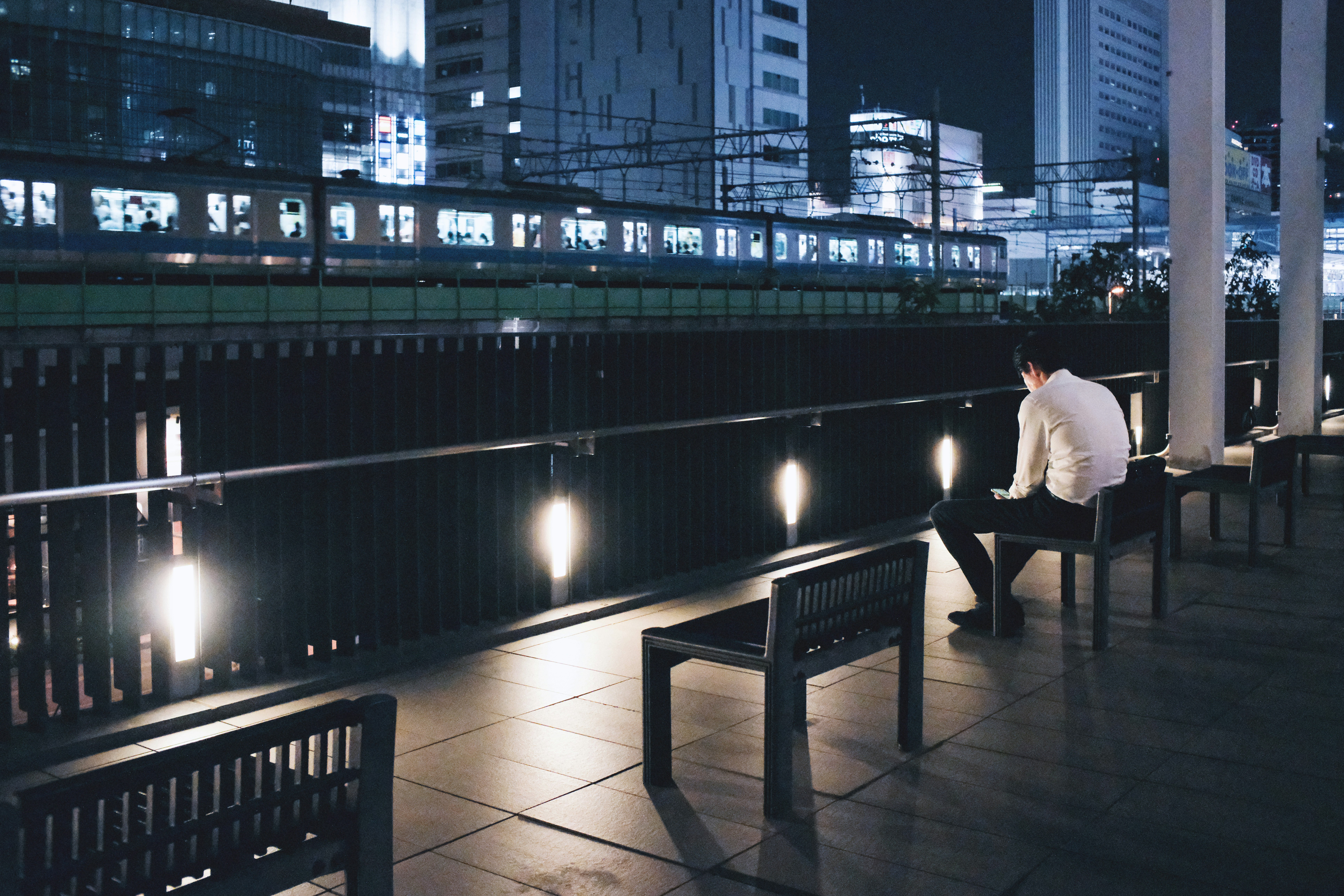 a person waiting on an outdoor bench at night
