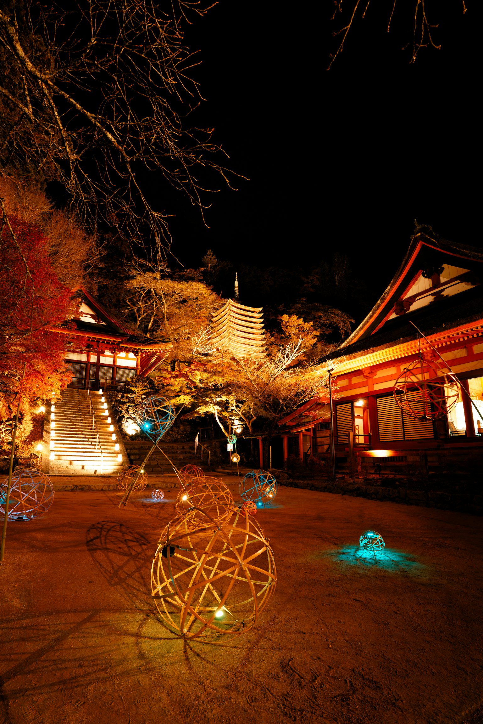 Colorful lights illuminating a temple courtyard at night with traditional architecture