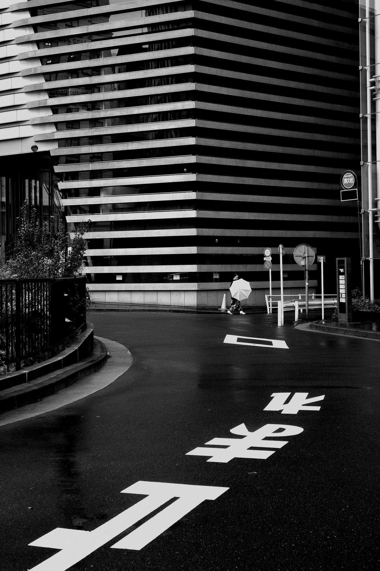 Monochrome urban scene featuring a winding road and a striped building