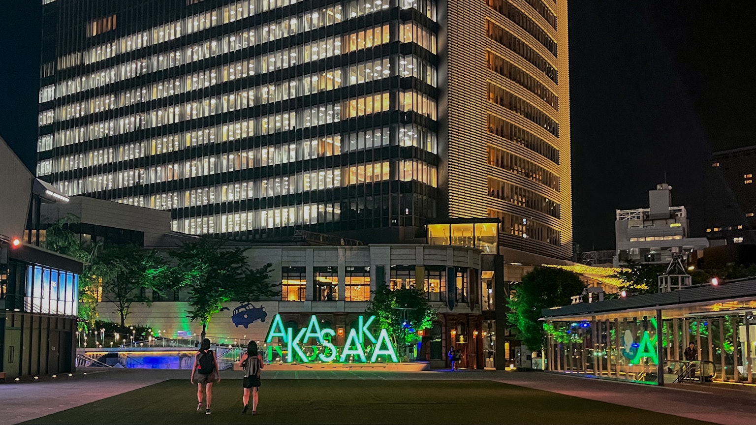 ฉากเมืองในตอนกลางคืนที่มีป้าย Aksaka สว่างและอาคารสมัยใหม่