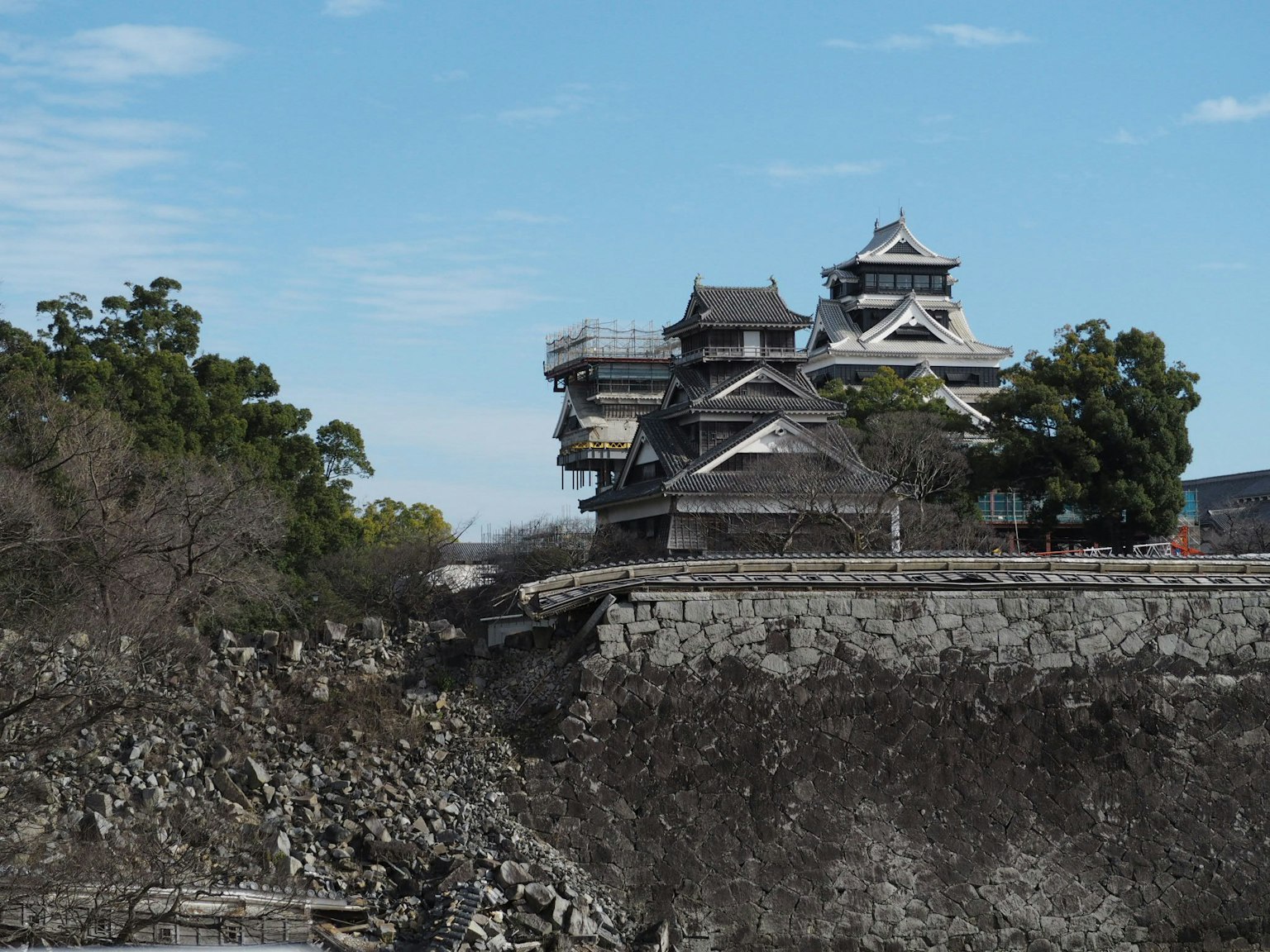 Vue du château de Kumamoto en restauration avec des murs en pierre et un ciel bleu