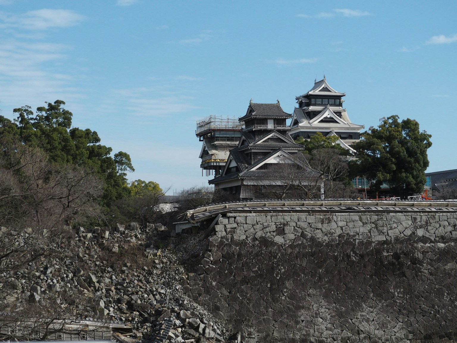 View of Kumamoto Castle under restoration with stone walls and blue sky