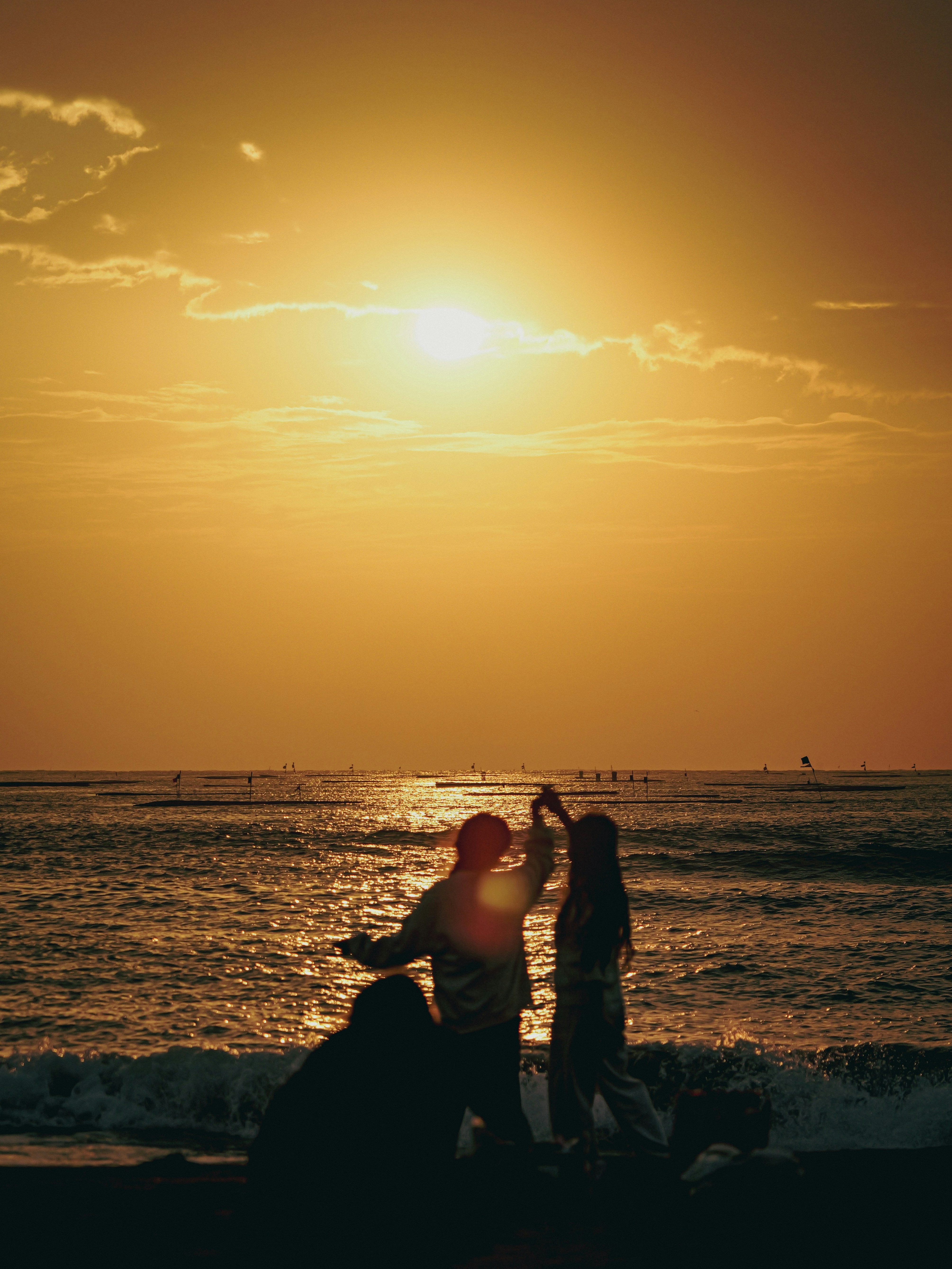夕暮れの海辺で寄り添うシルエットのカップル