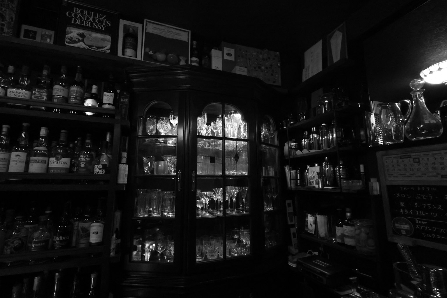 Interior de un bar oscuro con estantes de whisky y botellas