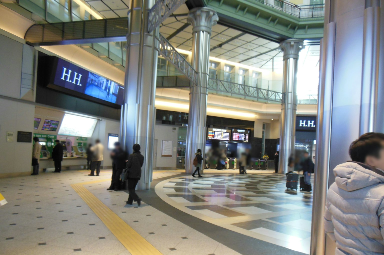 Intérieur spacieux d'une gare avec de nombreuses personnes et des colonnes distinctives