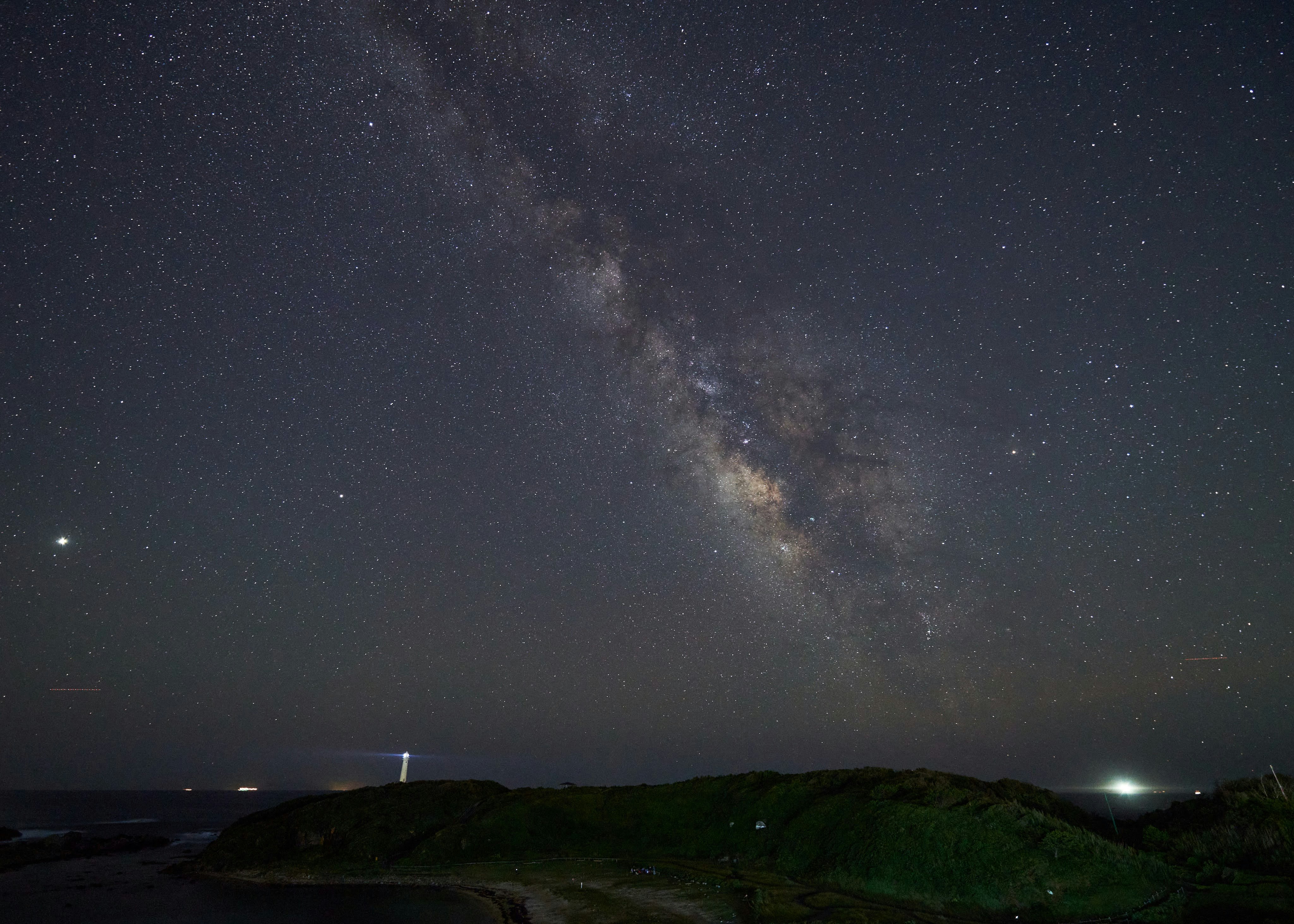 夜空に広がる天の川と星明かりの海岸の風景