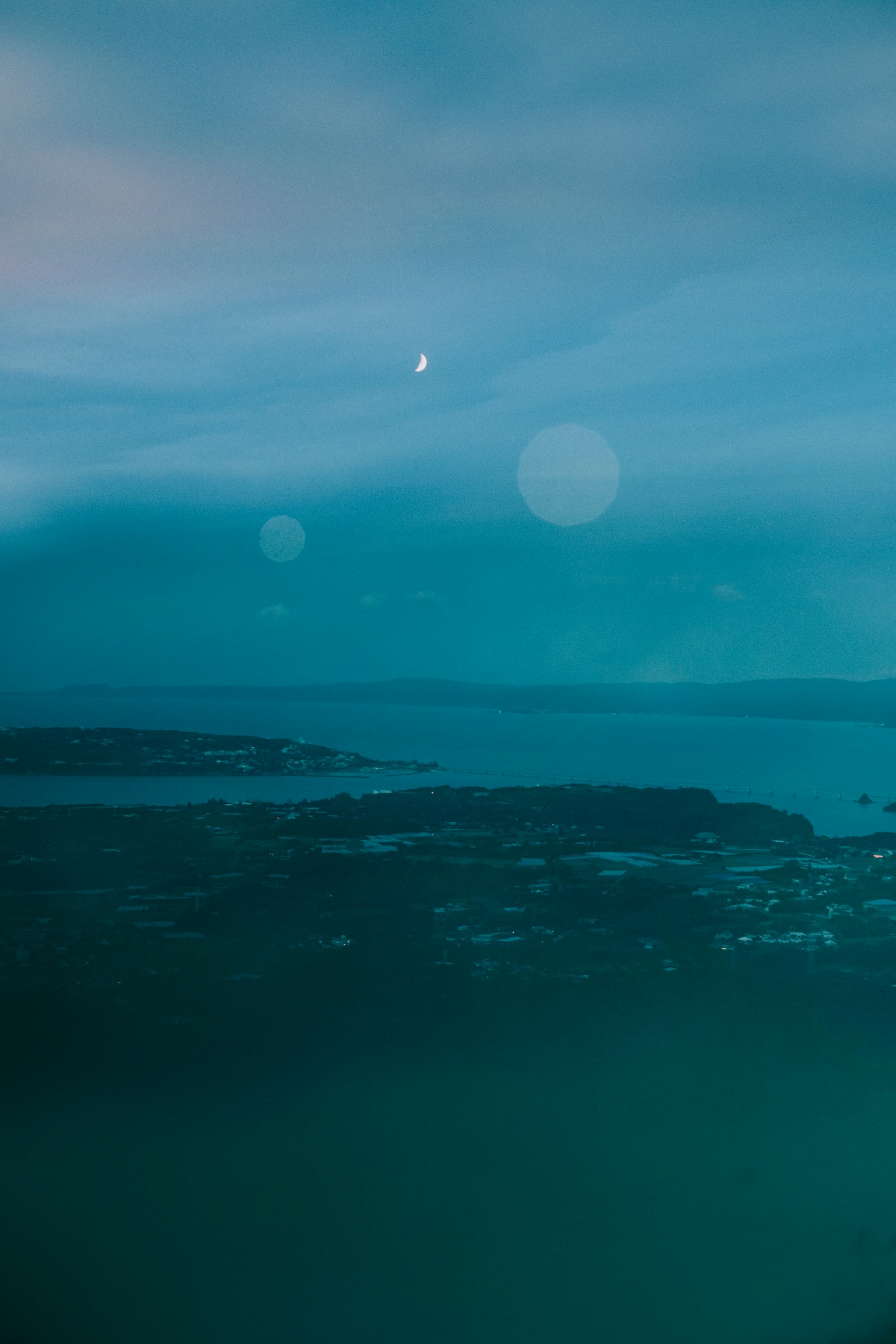 A serene view of blue ocean and sky with the moon shining