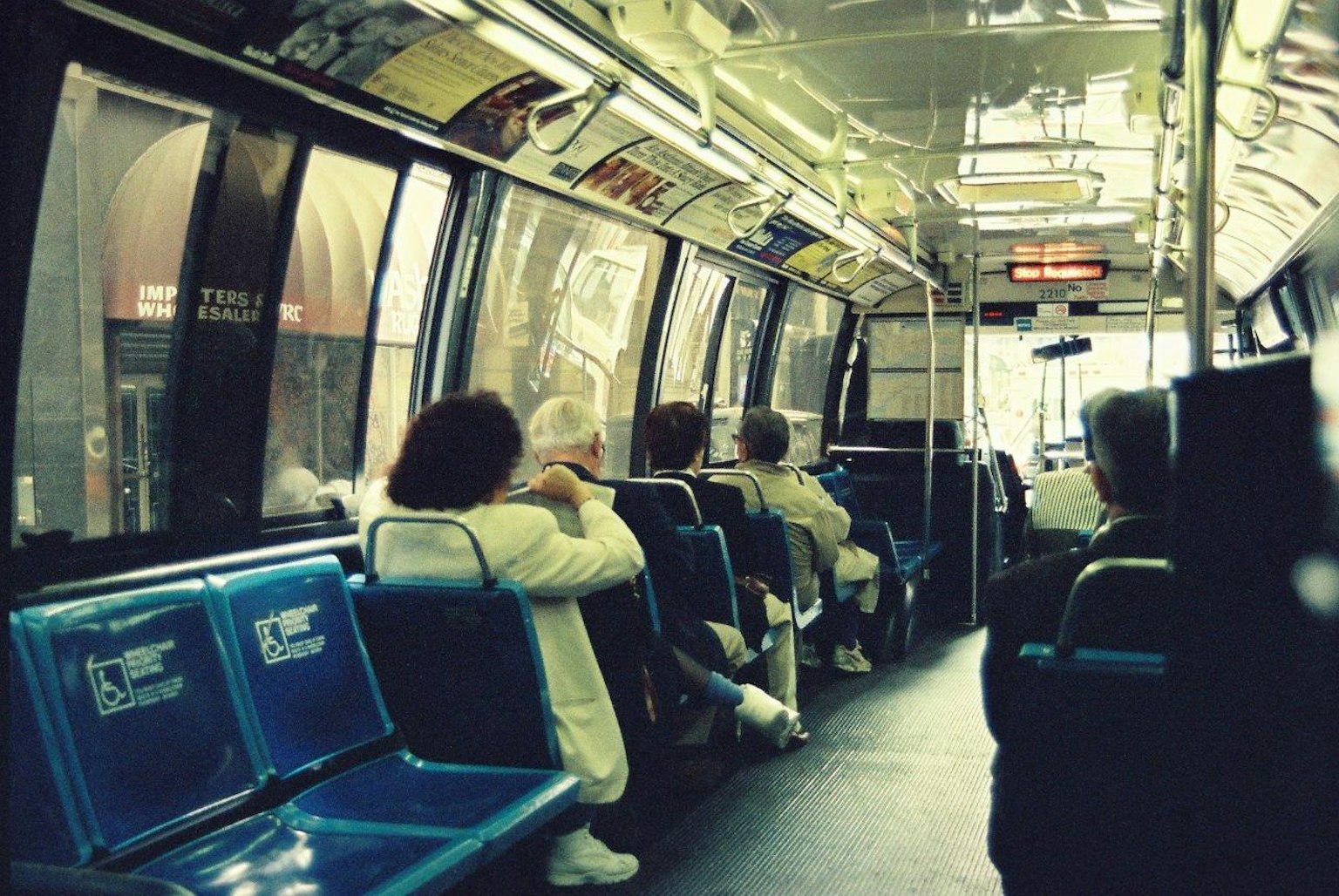 Intérieur d'un bus avec des passagers assis sur des bancs bleus grandes fenêtres visibles