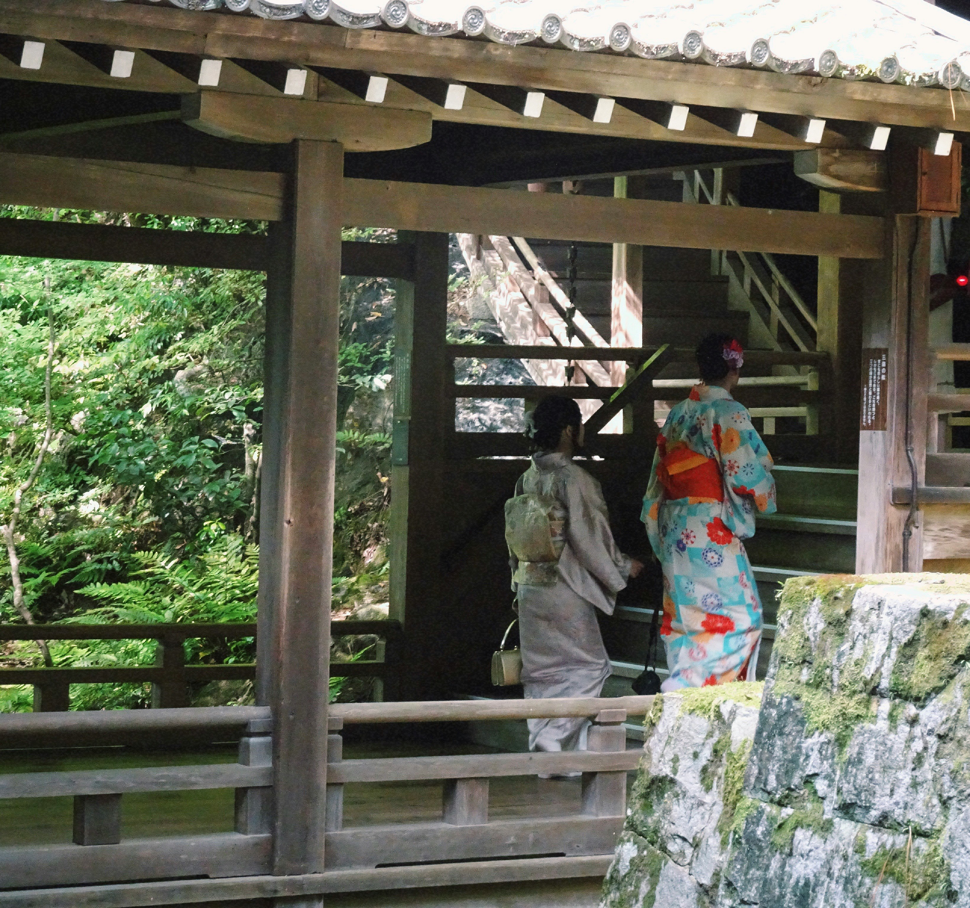 Gartenszene mit Menschen in Kimono in einem Holzgang
