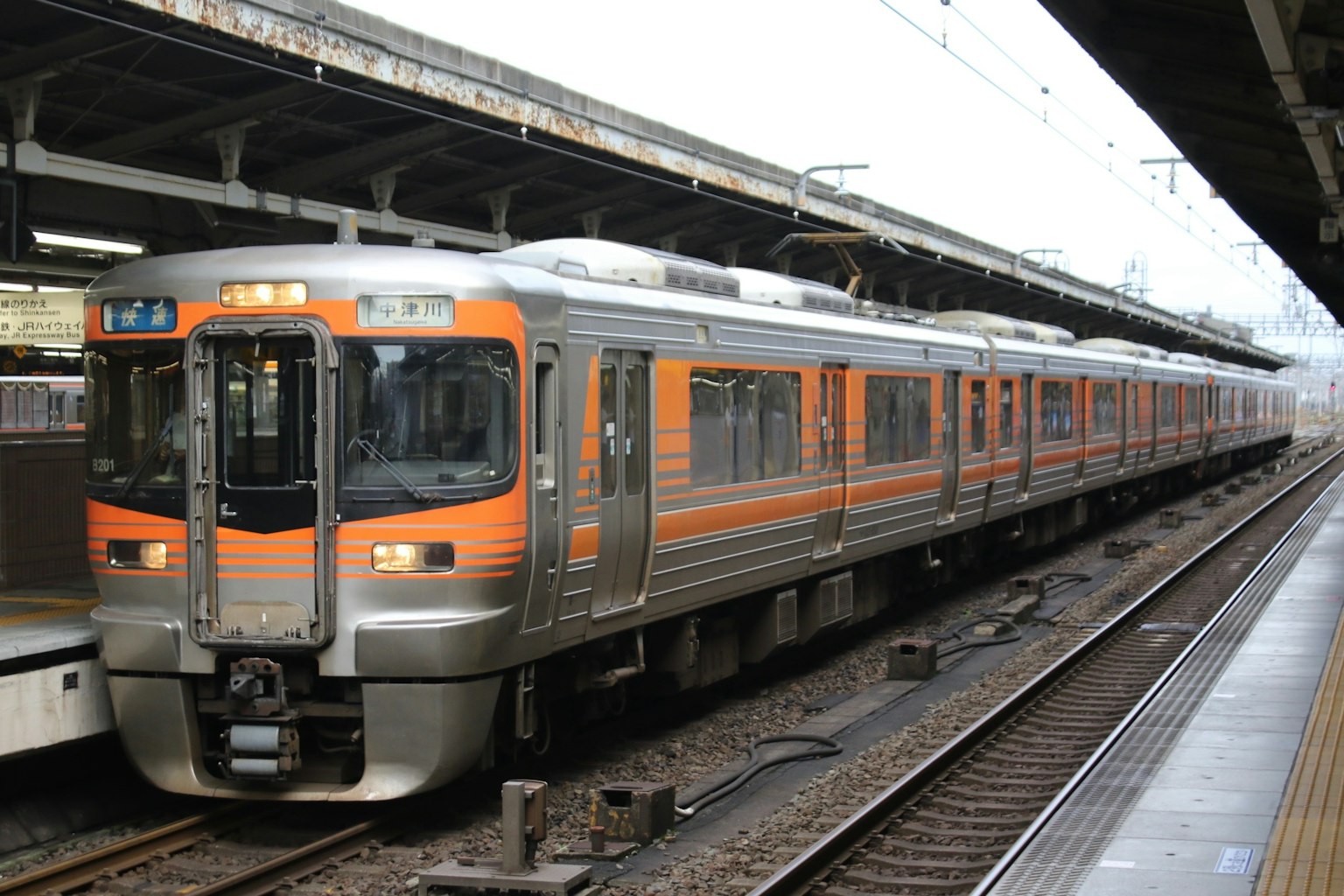 Un treno arancione e argento è fermo alla stazione