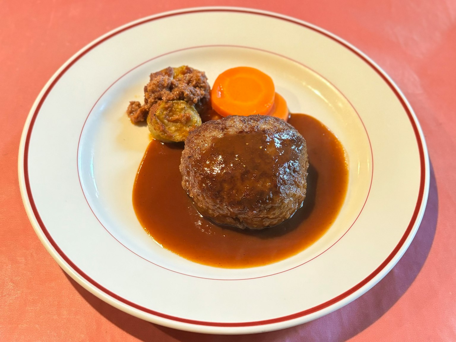 Leckeres Hamburgersteak mit Bratensauce, serviert mit Karotte und Beilage