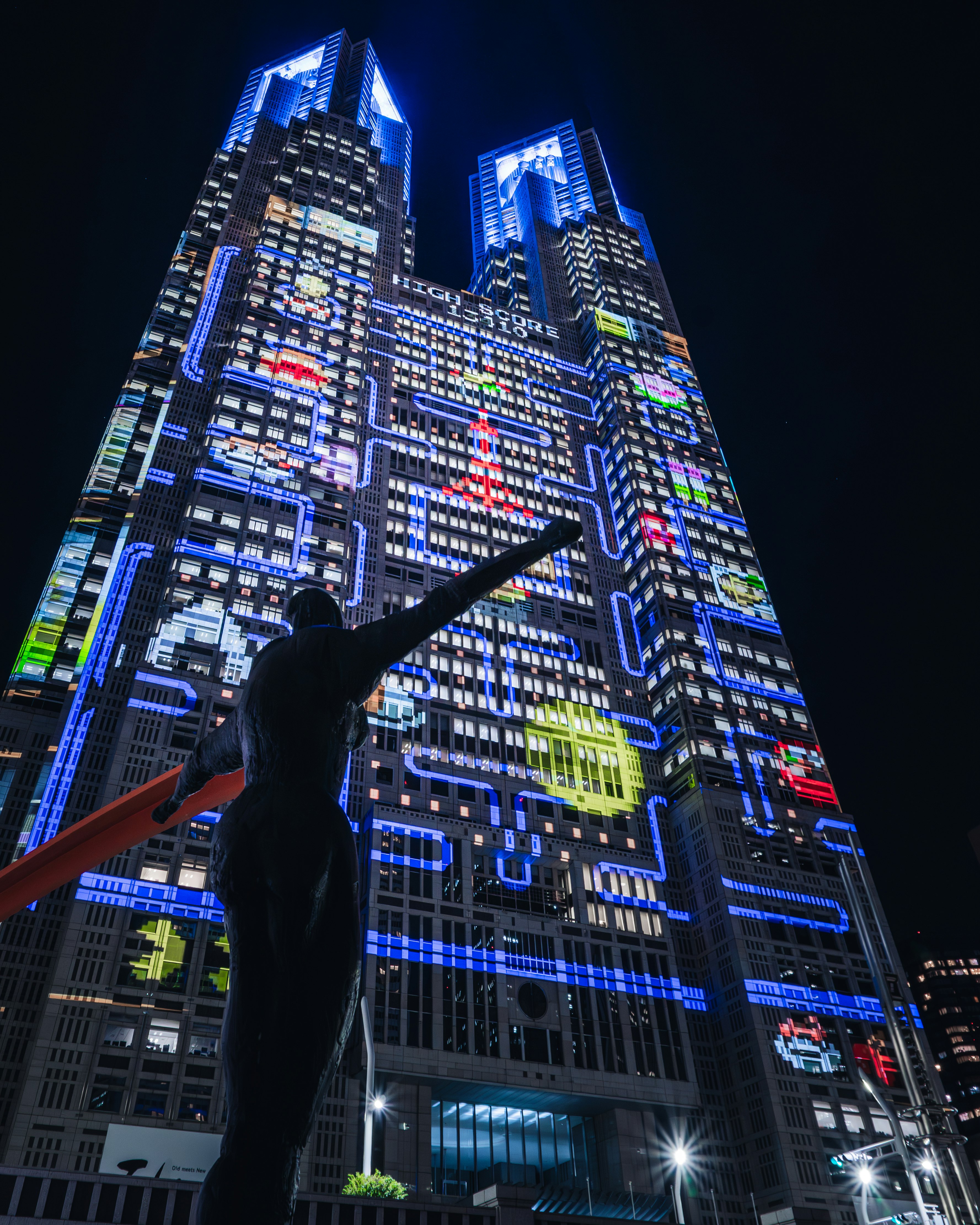 夜の都庁前で光るプロジェクションマッピングとパックマンのビル群