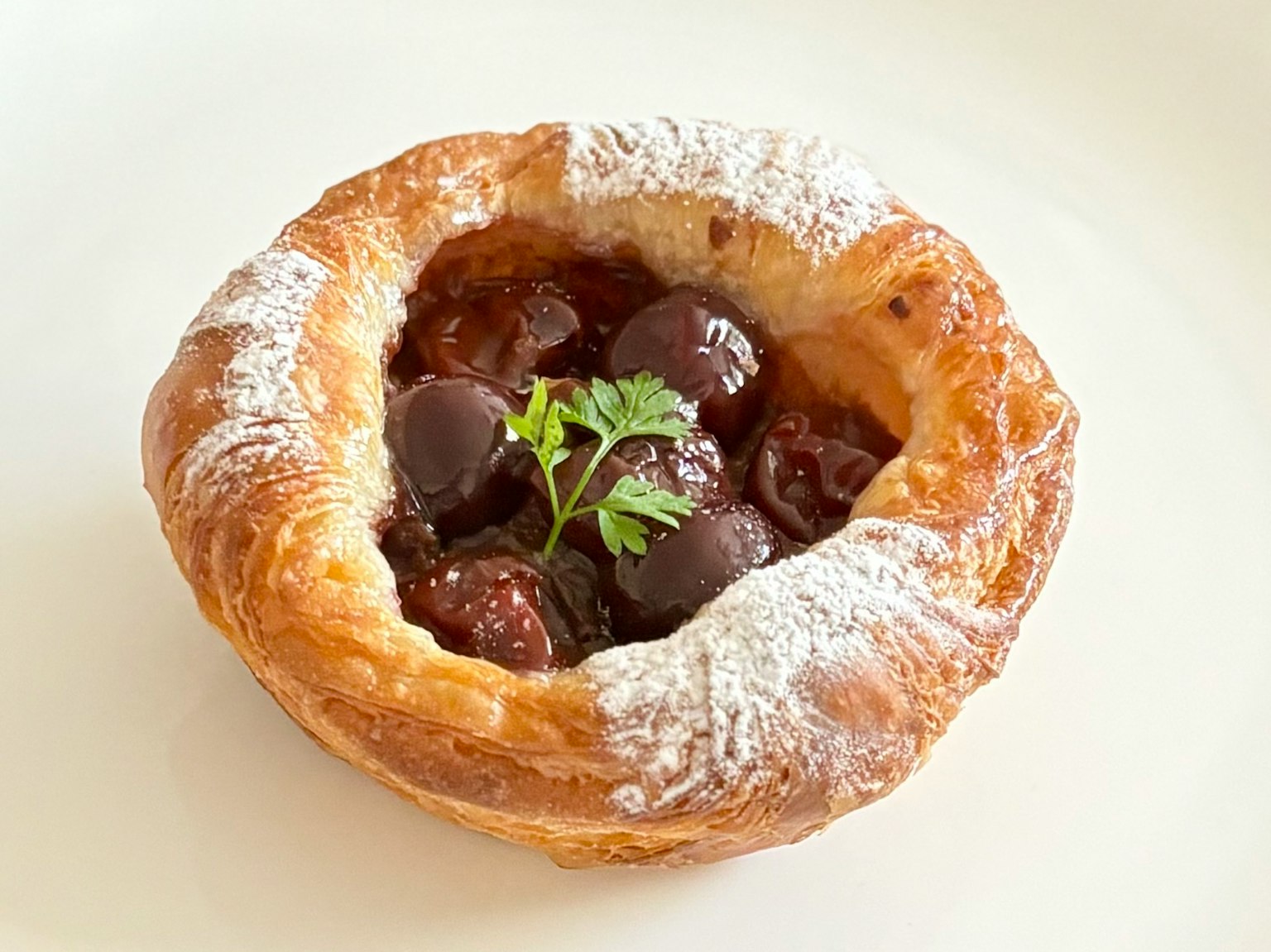 Deliziosa pasticceria ripiena di ciliegie dolci con una foglia di menta