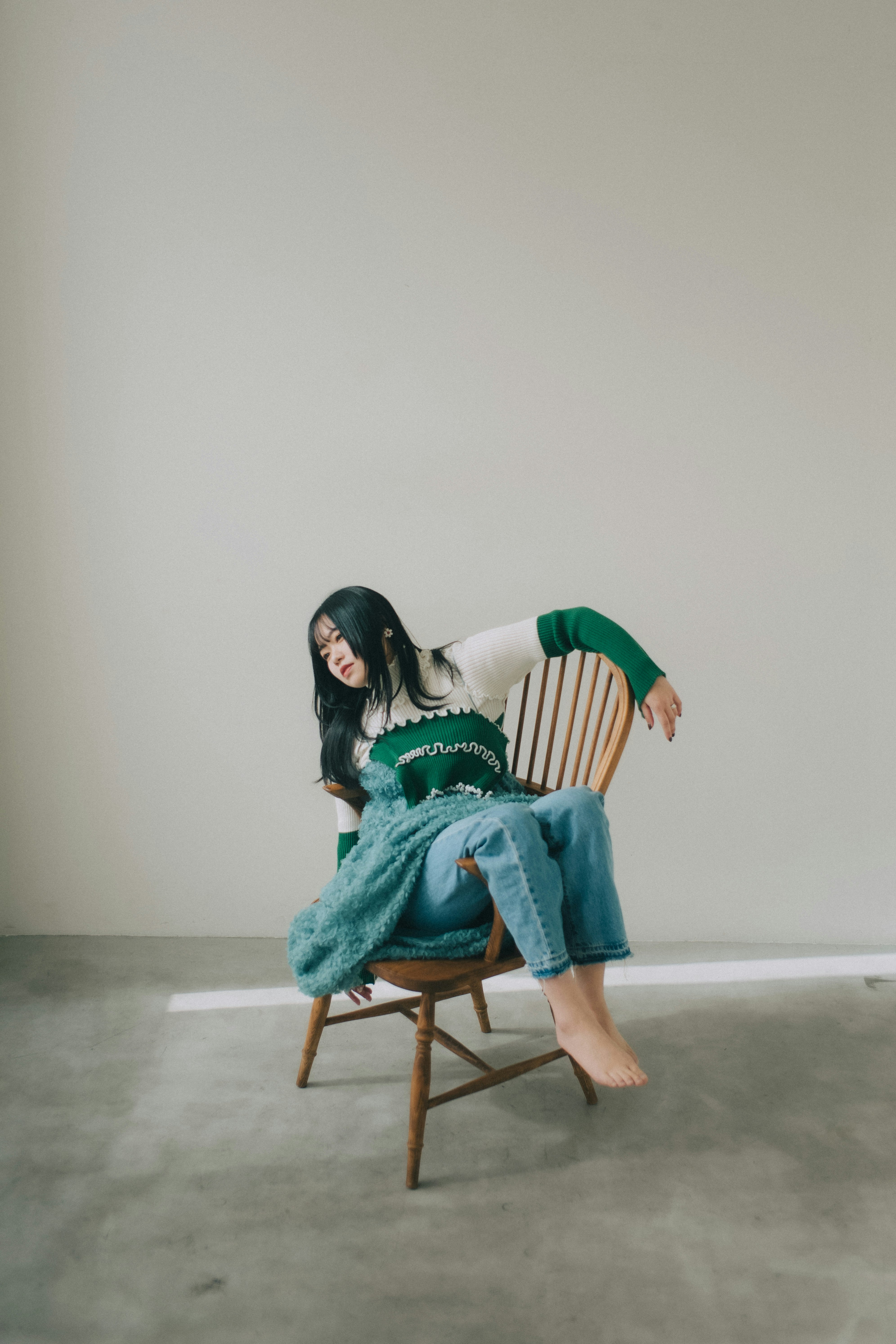 純色背景的攝影棚裡坐在椅子上的女性