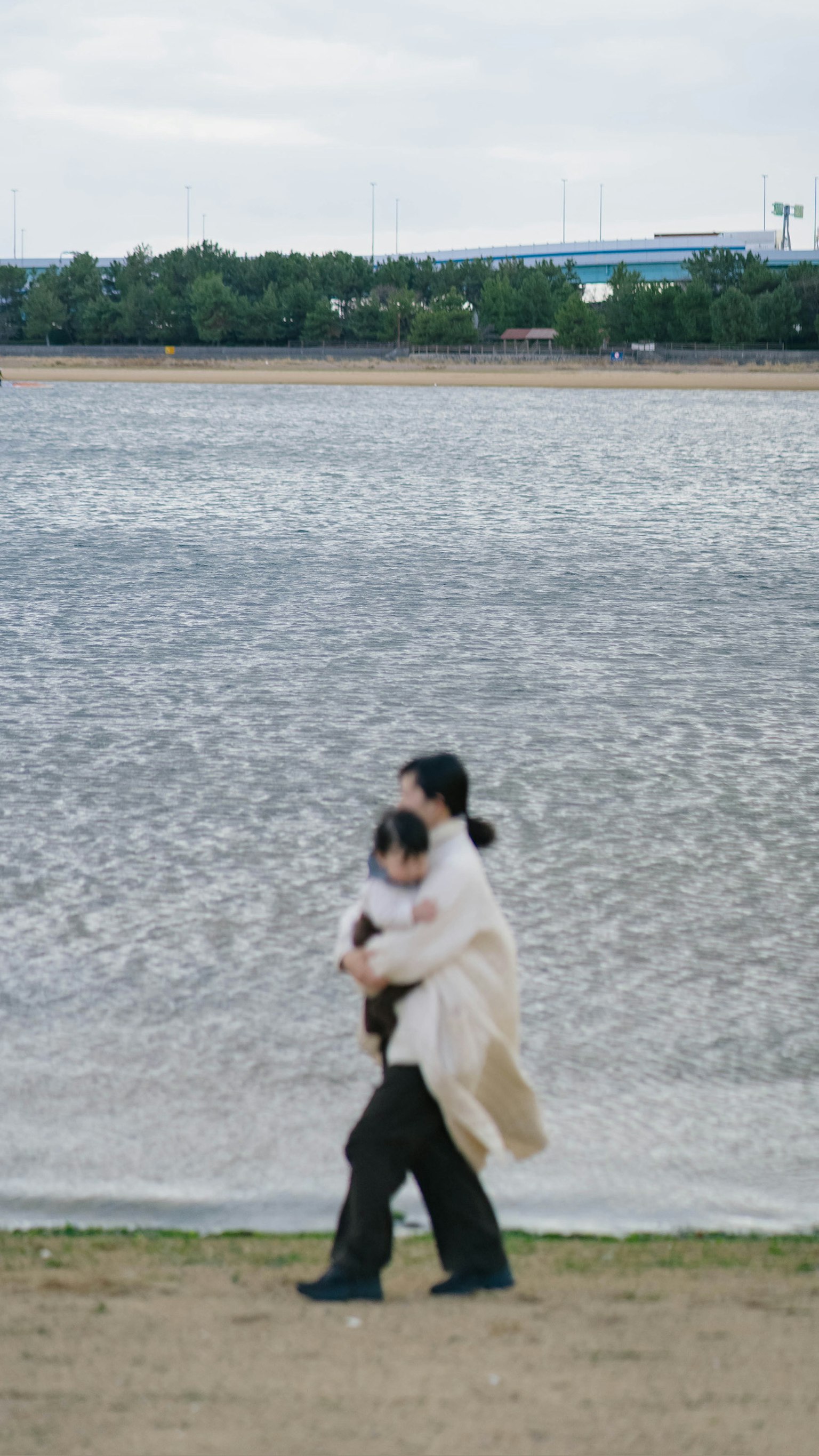 여성이 강가에서 아이를 안고 걷고 있는 모습