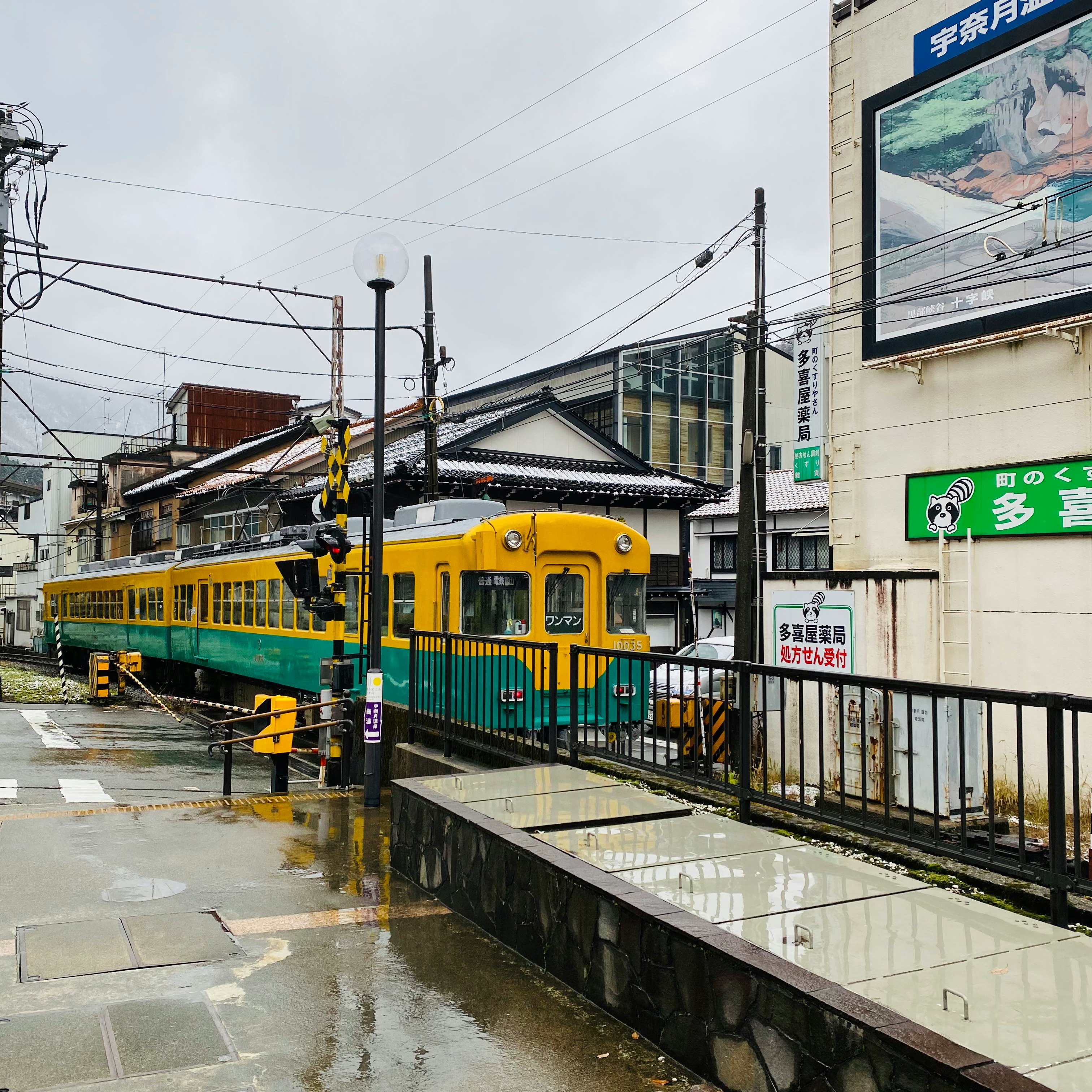 kereta trem kuning berhenti di peron stasiun saat hujan