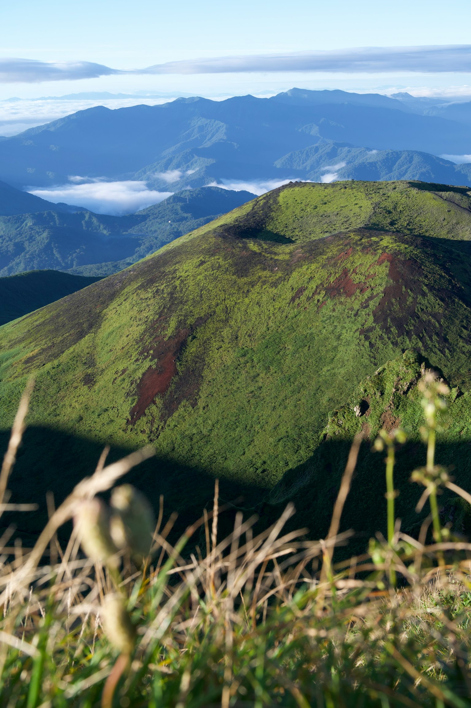 Paesaggio montano verdeggiante con un mare di nuvole