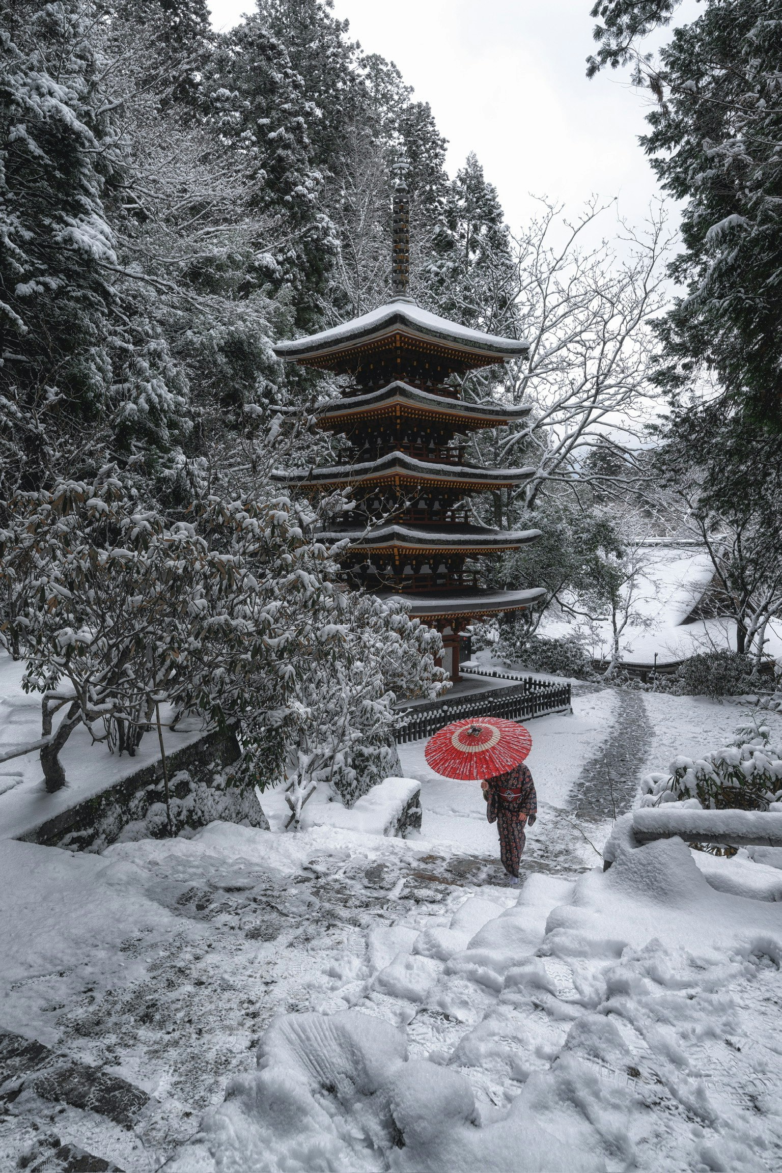 雪景色の中に立つ五重塔と雪道を歩く人