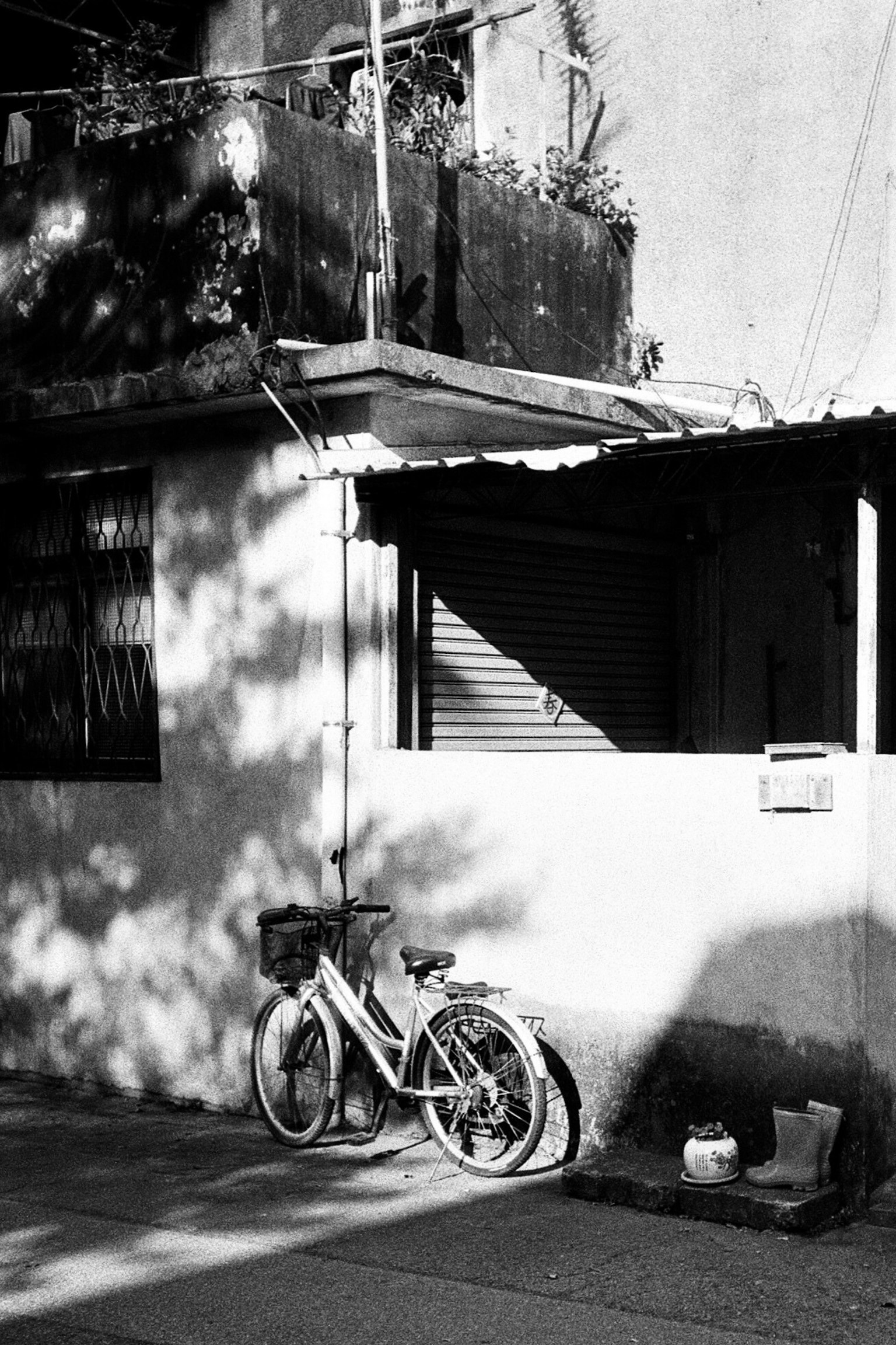白黒の自転車が壁に寄りかかっている風景 影が落ちる家の外観