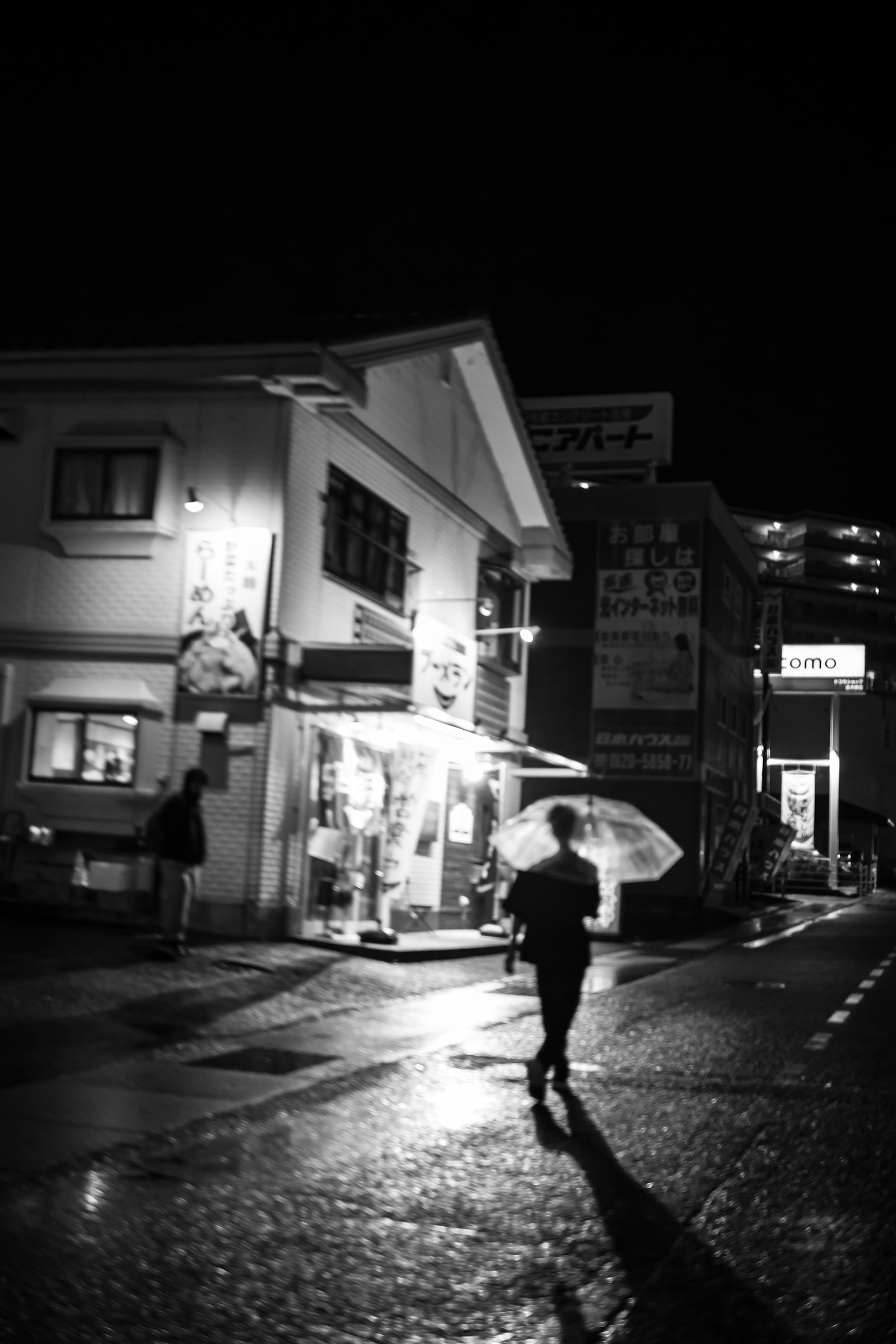夜间黑白街景，一人持伞