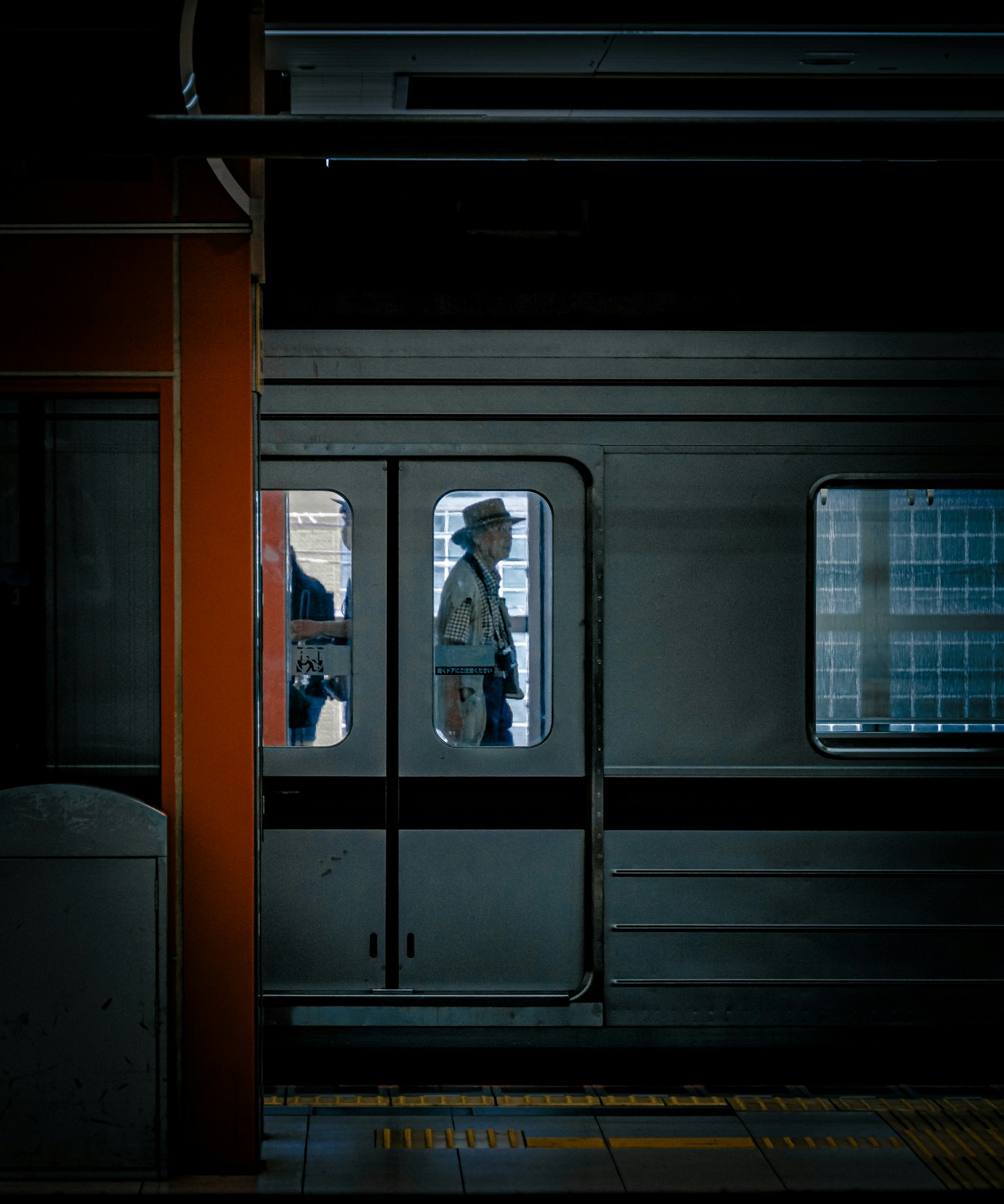 Silueta de una persona visible a través de una ventana del tren con fondo urbano