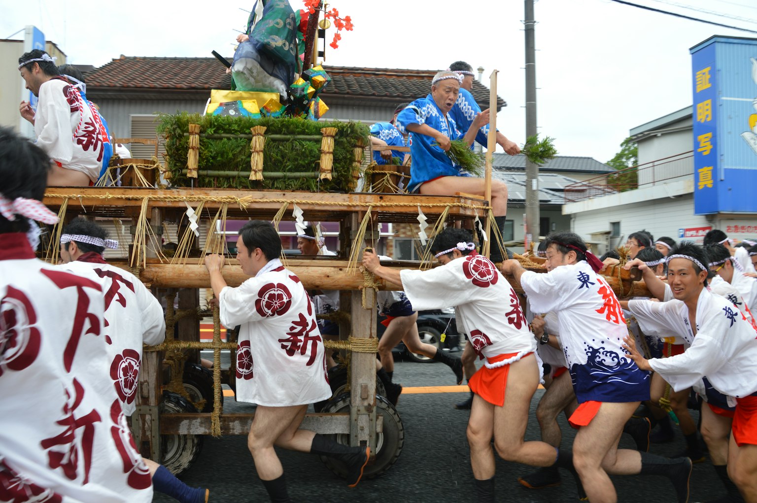 Orang-orang berpakaian tradisional menarik kereta festival