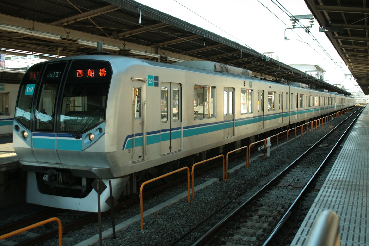 White train with blue stripes stopped at a station platform