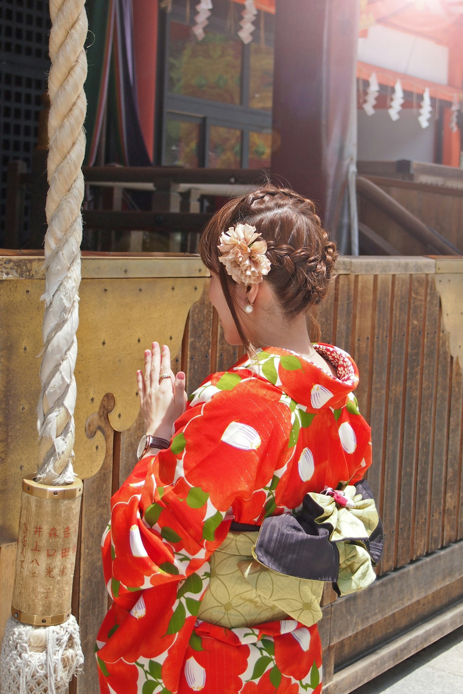 Wanita dalam kimono floral merah berdoa dengan tangan bersatu