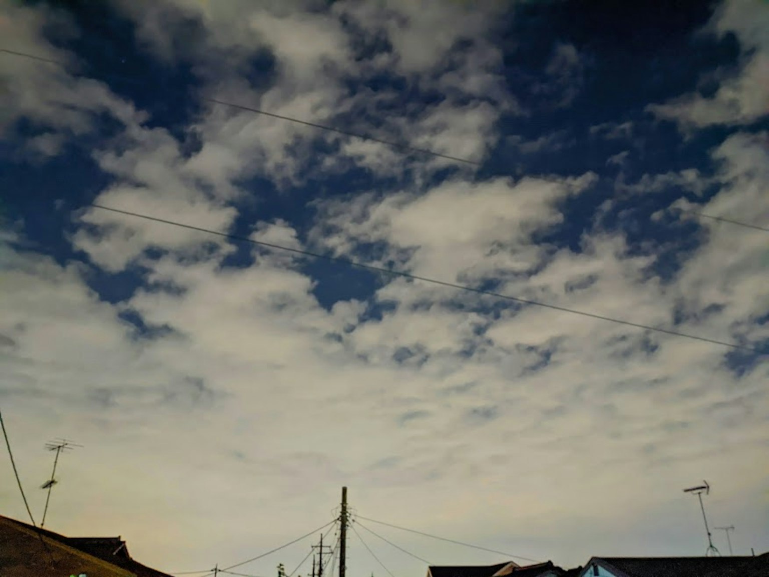 Eine Ansicht eines blauen Himmels mit weißen Wolken und Stromleitungen