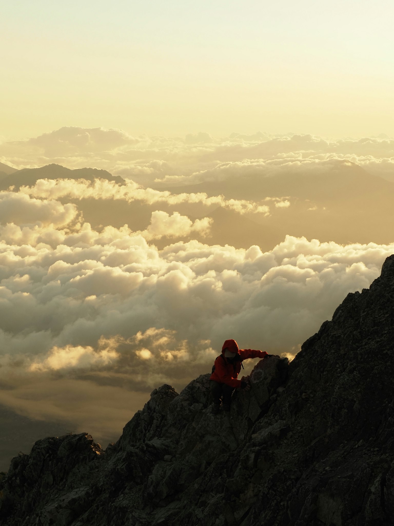 山の頂上で雲海を背景に登山者が岩を登っている