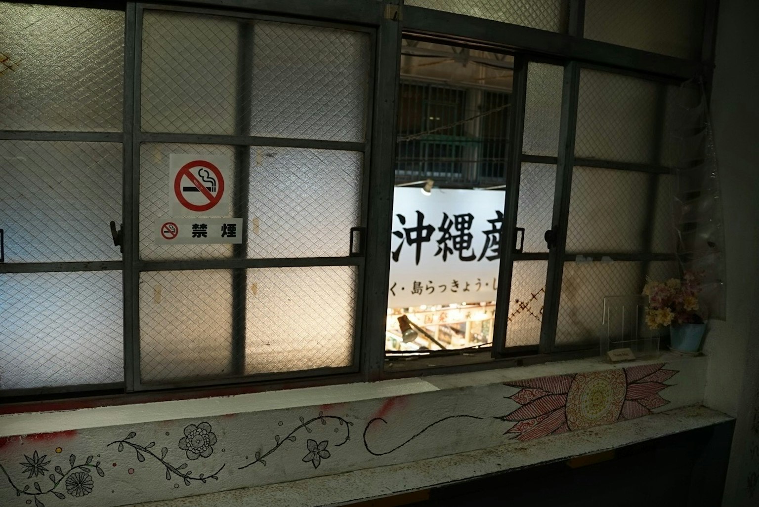 Interior view of an old building with a sign for Okinawa and a no smoking sign visible through a window